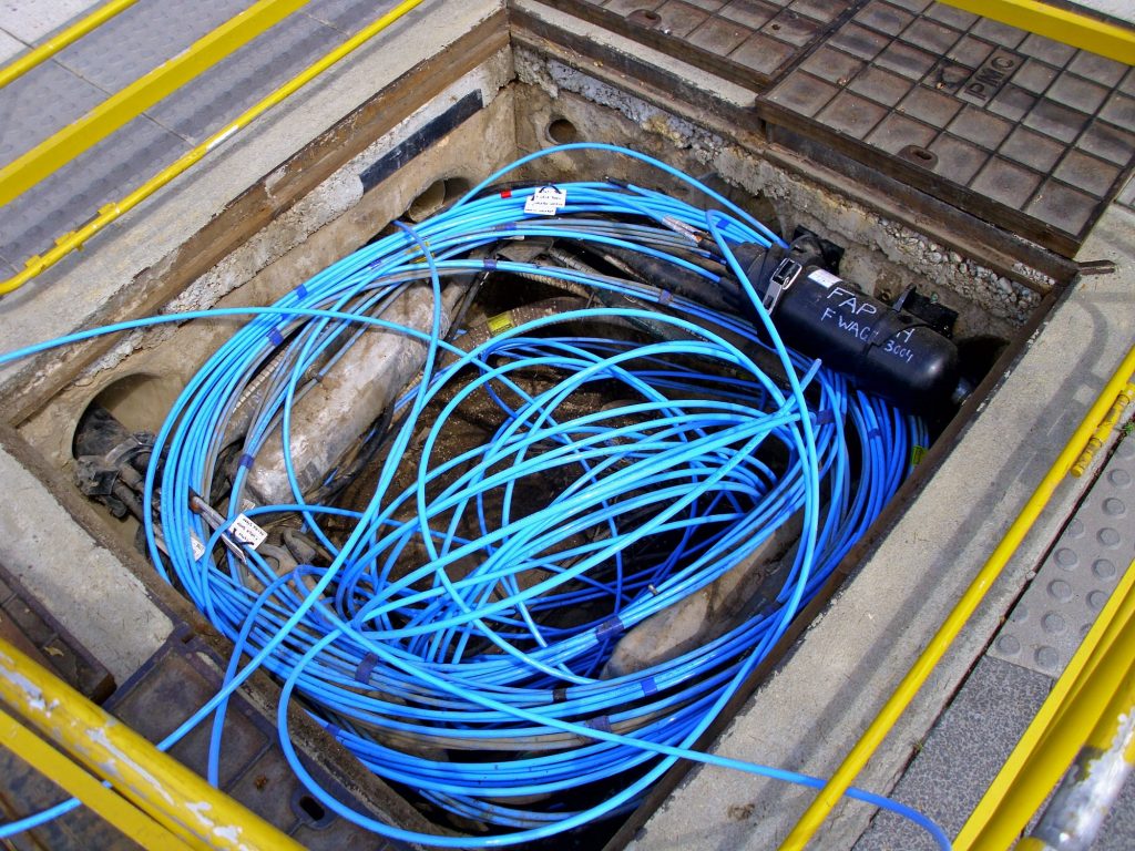 Fiberoptisk kabel installeras i en underjordisk grop. 