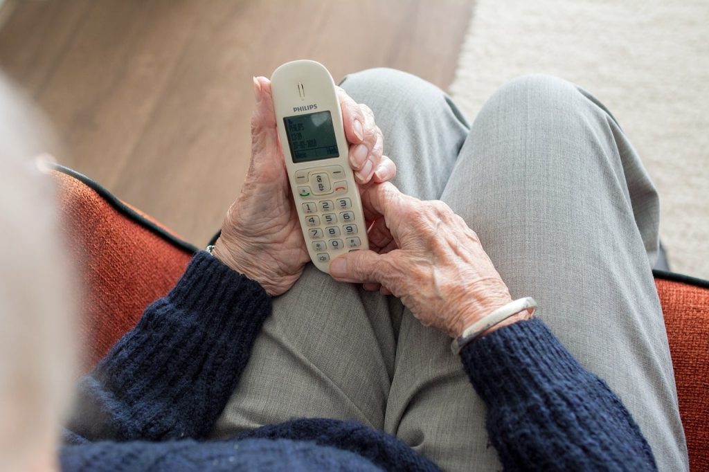 Äldre person använder sin hemtelefon.